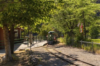 Green and yellow miniature train approaching the station in a sunny summer day in kamloops, british