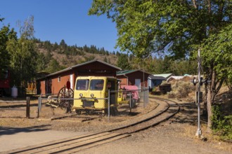 Old yellow locomotive and railway maintenance vehicles resting on a curved rail track in a kamloops
