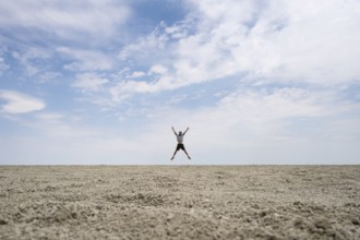Symbolic picture, abstract, man jumping on the Etosha pan, salt pan, Etosha National Park, Namibia
