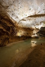 Stalactites and stalagmites, reflection in a small underground lake, rock formations in a