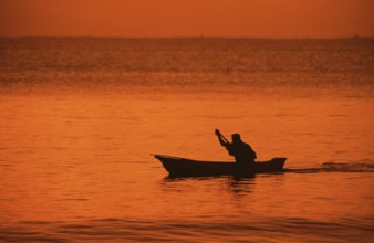 Silhouette of a fisherman in his boat at sunrise near Mikadi Beach, Dar es-Salaam, Tanzania,