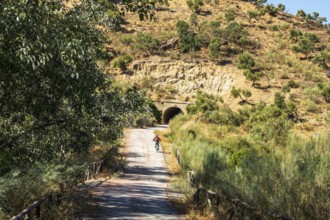 Woman riding a bycicle, cycle path Via Verde de la Sierra, path leads through a tunnel, Puerto