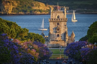 Scenic view of Belem Tower in Lisbon, Portugal, seen over a street with blooming purple jacaranda