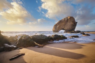 Penedo do Guincho, a large boulder rock arch at Praia da Santa Cruz, Portugal, with ocean waves and