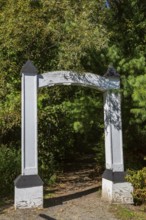White painted wooden portal gate at start of hiking trail in public nature park in late summer,