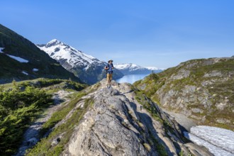 Hikers on Portage Pass, snow-covered mountains and Fjord Passage Canal, near Whittier, Alaska, USA