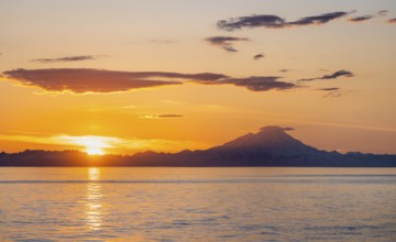 View of Cook Inlet on white mountain peaks of Mount Redoubt at sunset, picturesque golden light of