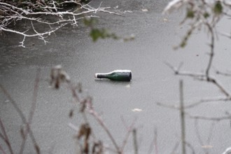 Symbolic picture of garbage in nature, bottle on frozen lake, winter, Germany