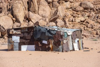 Simple poor huts made of corrugated iron and wood, desert landscape, barren landscape with hills of