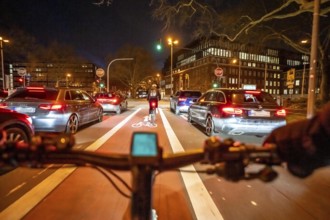 Cycling in the city, in the dark, in the evening, cycling on a bike lane, marked in red,