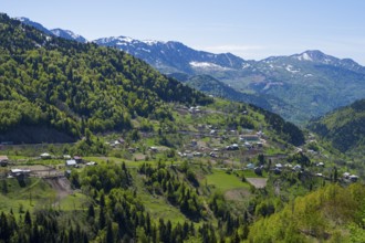 A small town is nestled in a green mountain landscape under clear skies, village in the Lesser