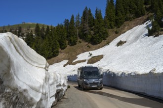 A van drives through a snowy road gorge surrounded by conifers, camper near Goderdzi on the way to