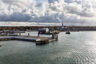 Ferry terminal, harbor with cityscape, St. Nicholas Church, dramatic cloudy sky, sunbeams, Rønne,