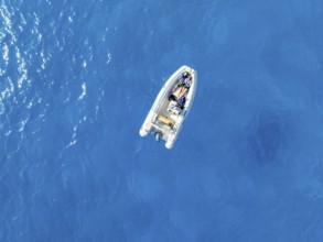 Young woman and young man lying in a motor boat on a blue sea, top-down, aerial view, Golfo di
