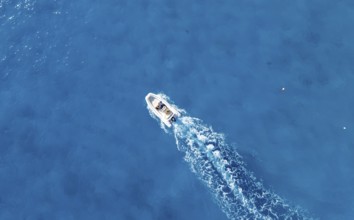 Motor boat riding on blue sea, top-down, aerial view, Golfo di Orosei, Baunei, Sardinia, Italy