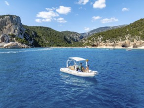 Motor boat off picturesque rocky coast, cliffs and Cala Luna beach, aerial view, Golfo di Orosei,
