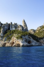 Picturesque rocky coast, cliffs with caves in the morning light, L'Aguglia rock peak, blue sea and