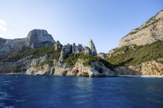 Picturesque rocky coast, cliffs with caves in the morning light, L'Aguglia rock peak, blue sea and