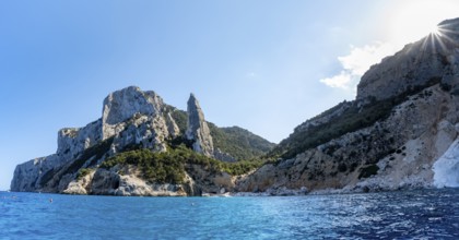 Picturesque rocky coast, cliffs with L'Aguglia pinnacle, blue sea and Cala Goloritzé beach, sun