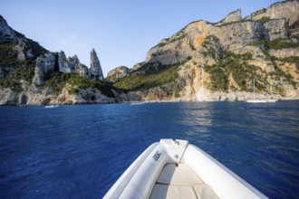 Motorboat trip along the picturesque rocky coast, cliffs with L'Aguglia pinnacle, blue sea and Cala