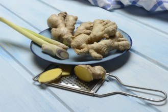 Ginger tubers and lemongrass on plate, grater with ginger pieces