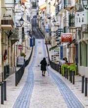 Sticker-covered sign with bicycles and surfboards, Nazaré, Portugal