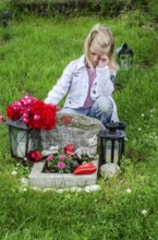 Grieving blonde 7-year-old girl at her cat's grave at pet cemetery in Ystad, Skåne County, Sweden,