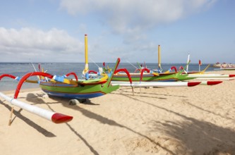 Colourfully painted outrigger fishing boats, (Junkung), on Sanur beach, Bali, Indonesia