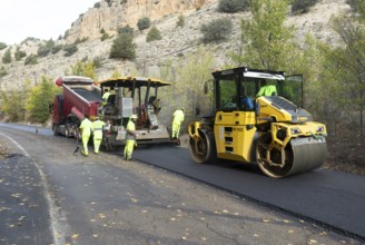 Asphalt road construction team of workers resurfacing tarmac in rural area, near Albarracin, Teruel