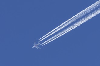Airbus A380 jet passenger aircraft of Emirates airlines flying in a blue sky with contrails or