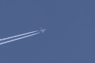 Airbus jet passenger aircraft flying in a blue sky with contrails or vapour trails behind, England,