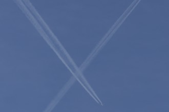 Aircraft contrails or vapour trails crossing in a blue sky, England, United Kingdom