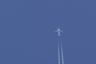 Boeing 737 jet passenger aircraft of Norwegian Air airlines flying in a blue sky with contrails or