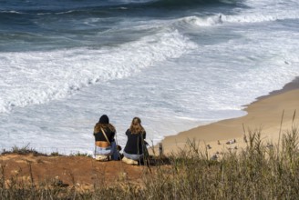 Tourists watch the waves of the Atlantic on the rocky plateau of Sito, also known as Forte São