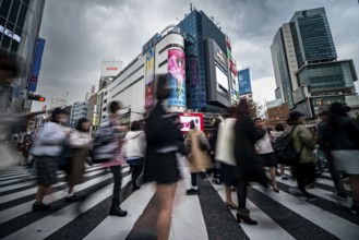 Crowd crossing zebra crossing on a large intersection, motion blur, back modern houses with