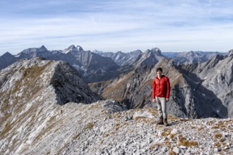 Hikers on the summit ridge of the Gamsjoch, behind rock faces of the Laliderer Spitze, eastern