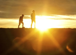Woman and child walk across a dike on the island of Fehmarn at sunset, 13.10.2025, Fehmarn,