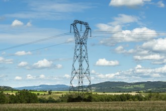 High voltage power lines against a bright blue sky with scattered clouds, Puy de Dome, Auvergne