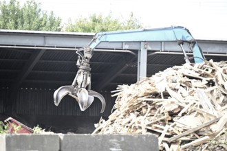 Loading crane with grab arm for loading wood waste for wood pellet production on the premises of