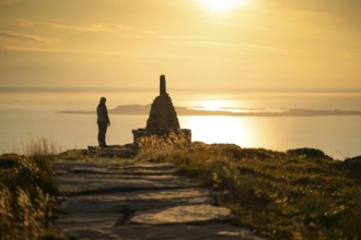 Woman standing next to cairn and looking at the sea, Rørsethornet stone staircase, with 3292 steps
