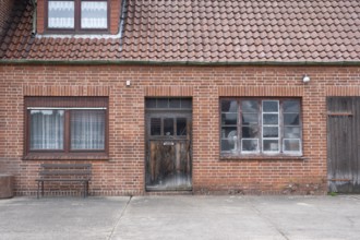 View of the entrance area of an older residential building with a red brick workshop, Uenzen,