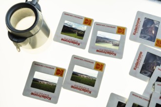 Many framed Kodachrome slides on a light table with magnifying glass, top shot