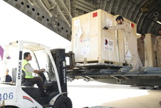 Members of the Qatari Air Force unload humanitarian aid supplies from a transport aircraft at