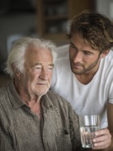 A young carer lovingly looks after a senior in an old people's home, nursing home, symbolic image