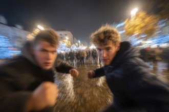 Two men in fighting pose on a rainy street at night, surrounded by lights, symbolic image for