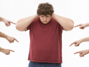 Overweight boy being judged by pointing fingers, symbolising fatshaming, bullying, judgement and