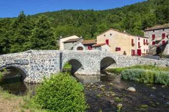 Stone bridge over the Pavin couze river flowing through the village of Saurier, Puy de Dome.