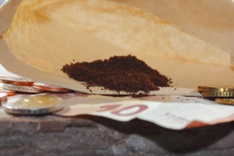 Ground coffee in a filter bag with coins and a ten euro note in front of it, North