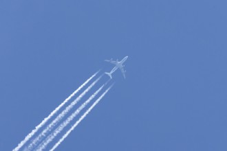 Airbus A340-300 jet aircraft of Lufthansa airlines in flight in a blue sky with vapour trails or