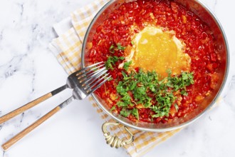 Traditional Turkish dish, scrambled eggs with tomatoes, Menemen, with herbs, in a frying pan,
